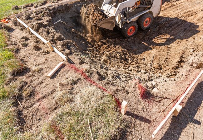 Small Bulldozer Digging In Yard For Pool Installation.